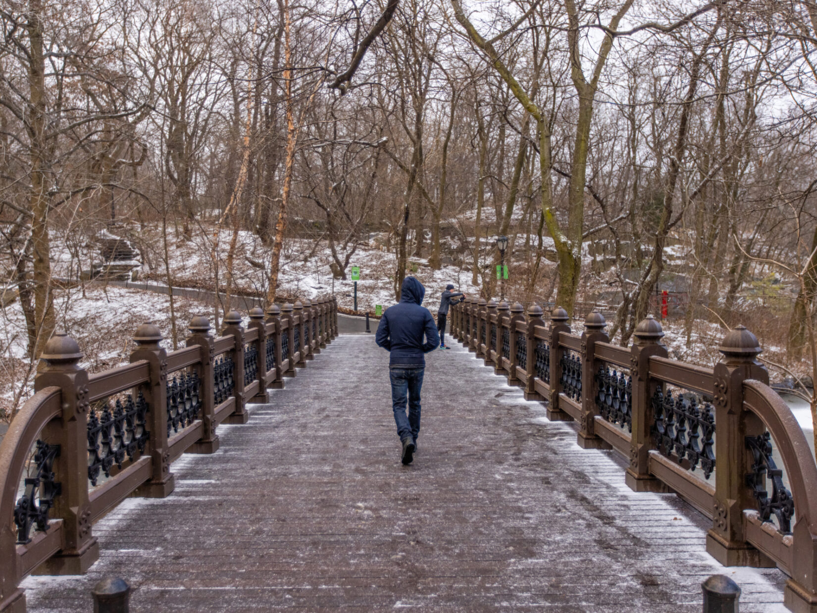 A person walks over a snowy bridge.