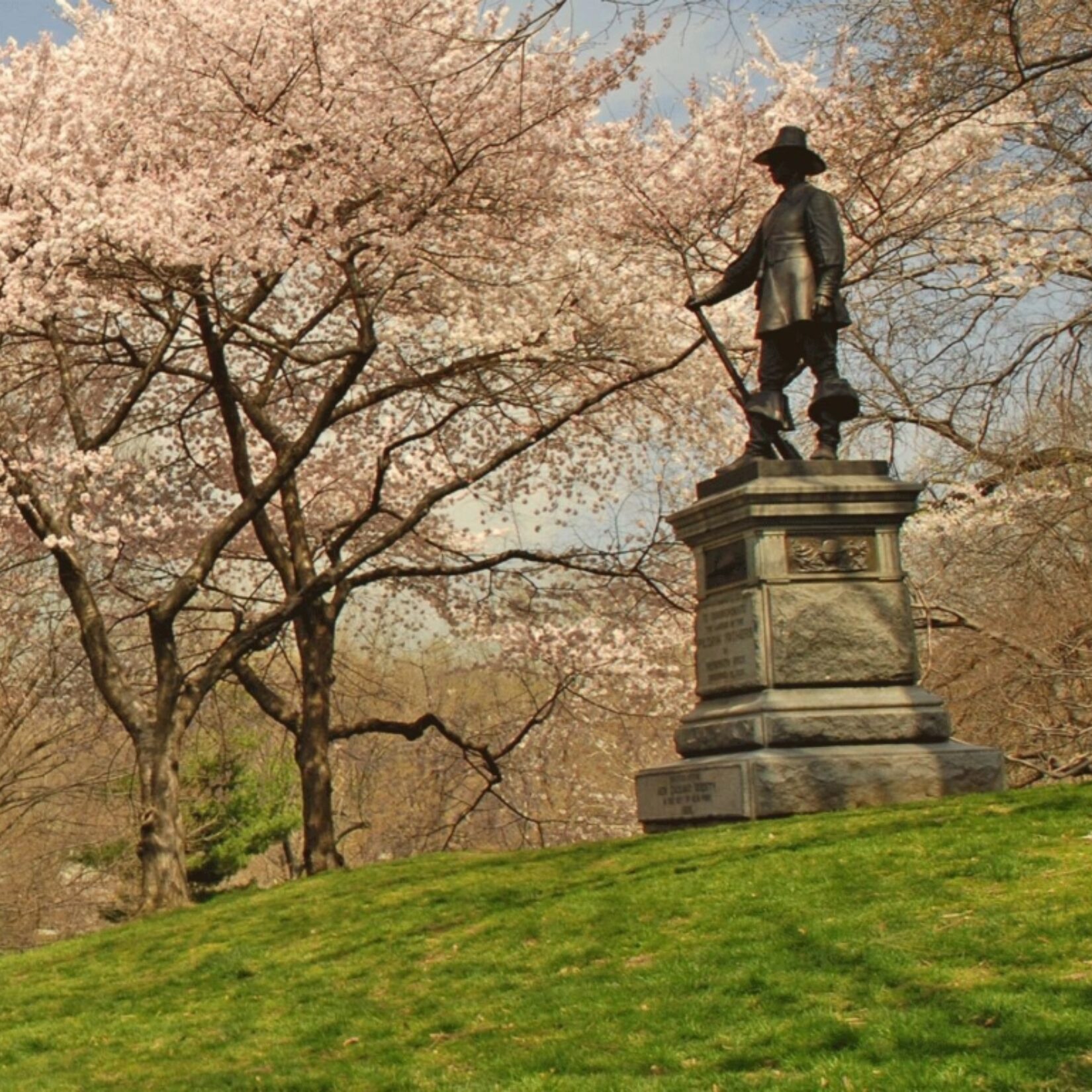 Trees sprouting pink, spring buds line the slope of the hill to the eponymous statue at the crest.