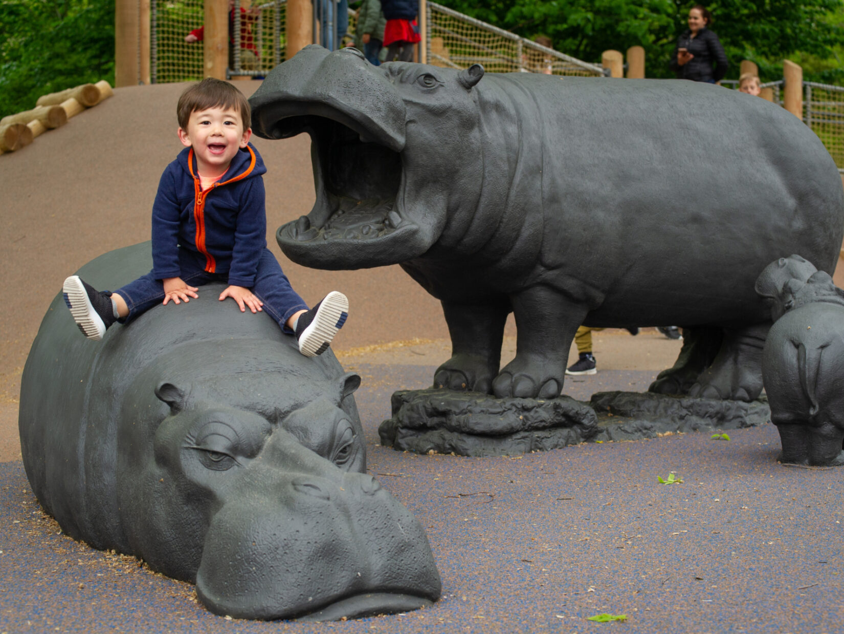 A child sits one of the hippos the populate the Safari Playground