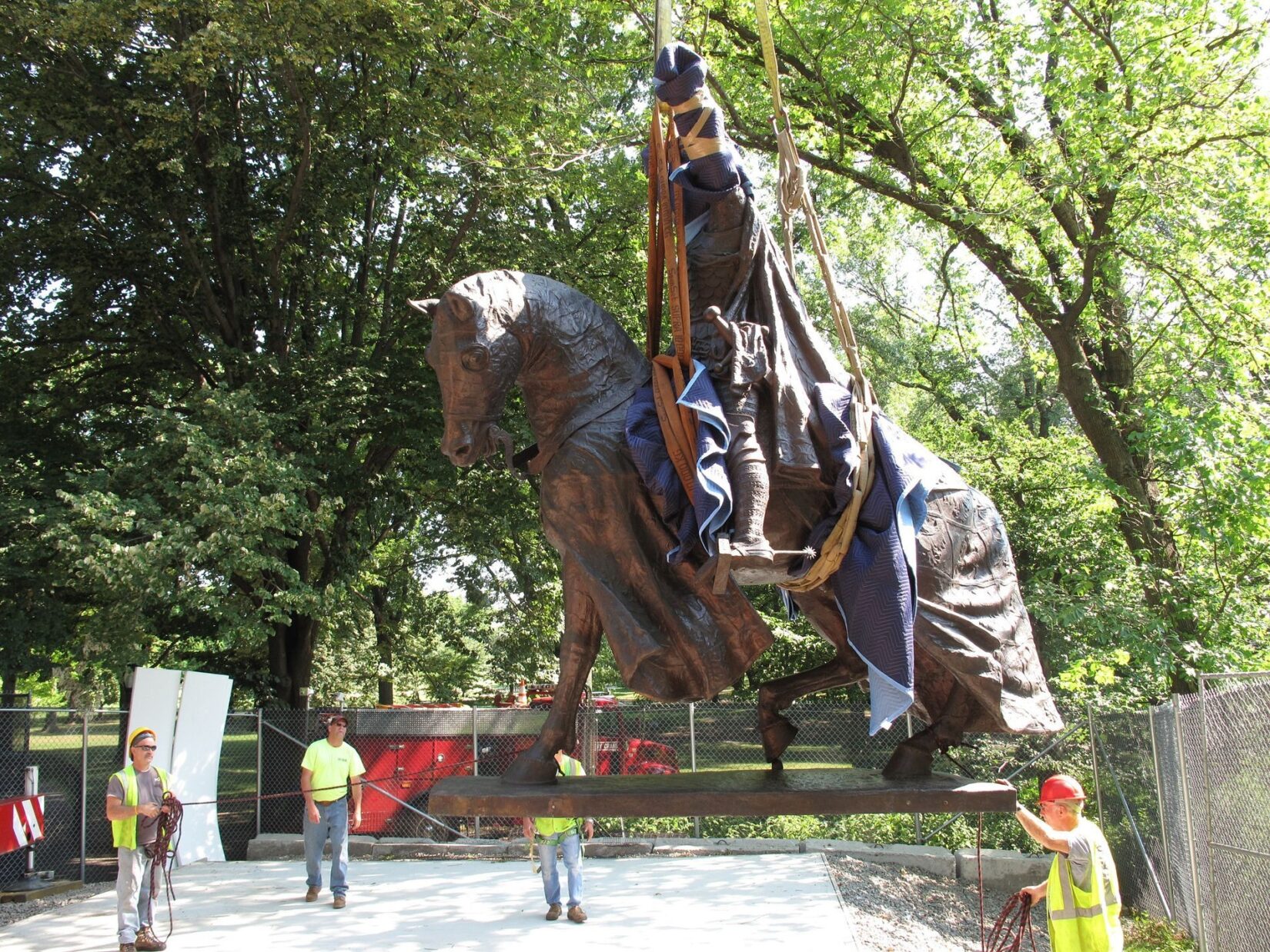 The statue is held in mid-air by a crane.