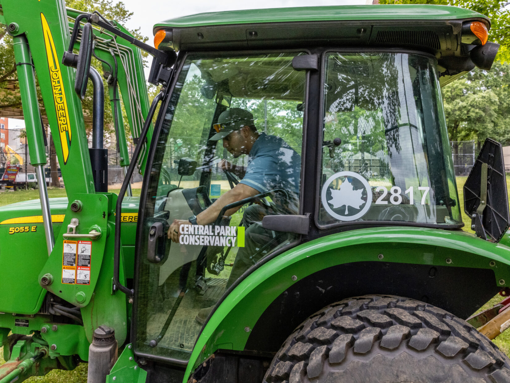 A man operates a large green machine in a park.