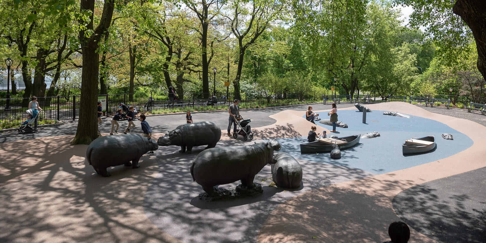 A long view of the playground, with children enjoying the hippos and simulated water area