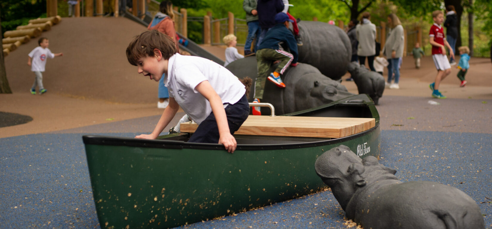 A young boy enjoys a boat-like feature of the playground