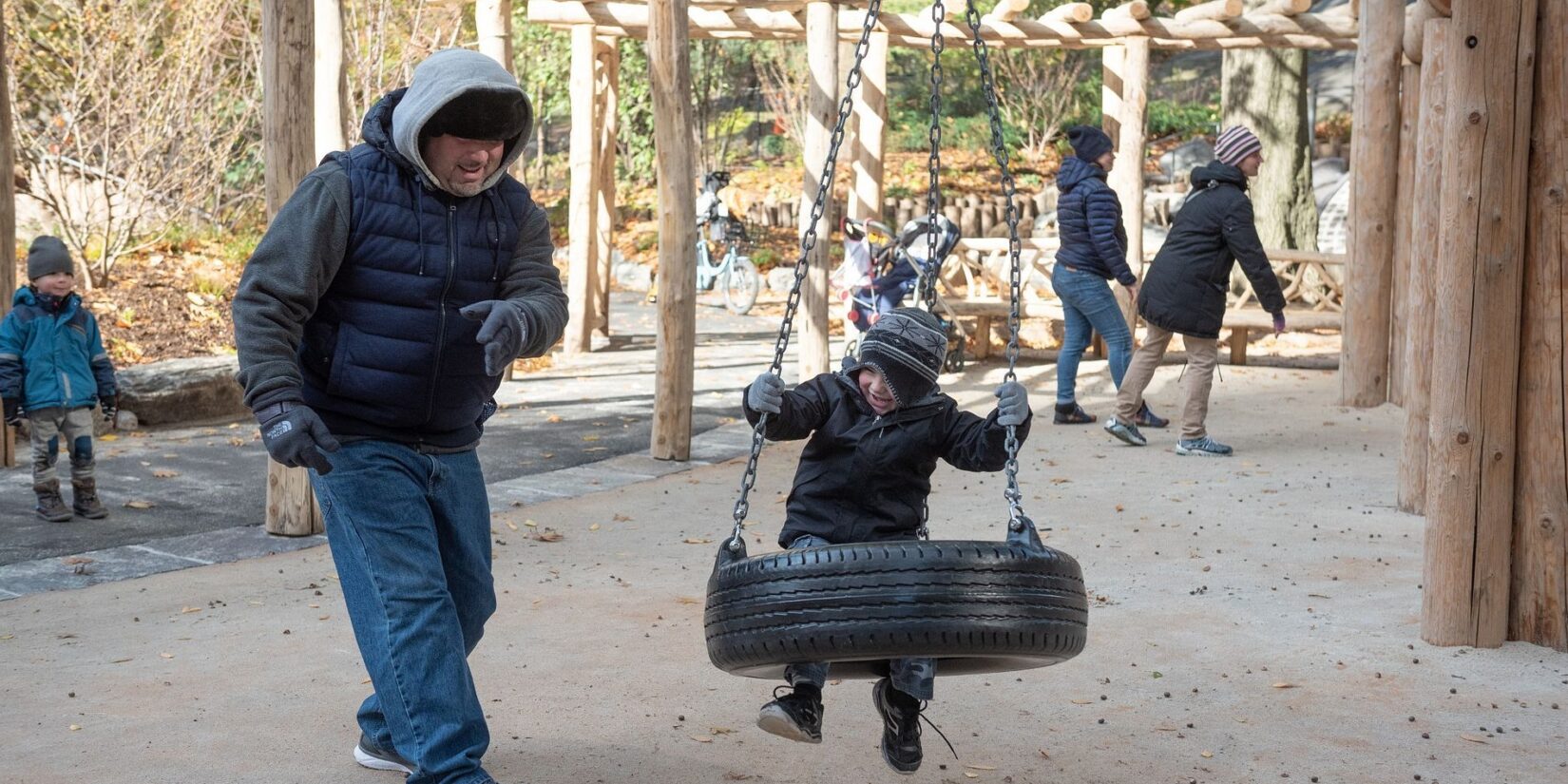 A young boy enjoys a tire swing in early spring.