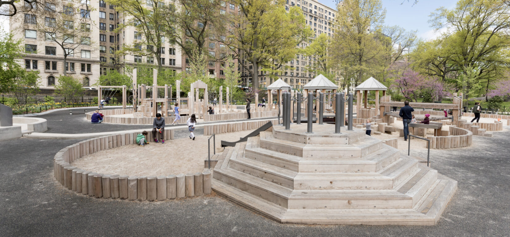 Children playing on the wooden structures of the playground, in early spring