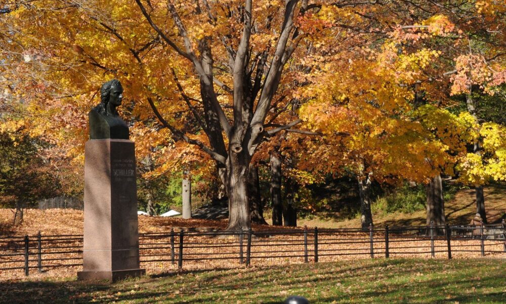 The bust is seen against a background of autumnal foliage on the Mall.