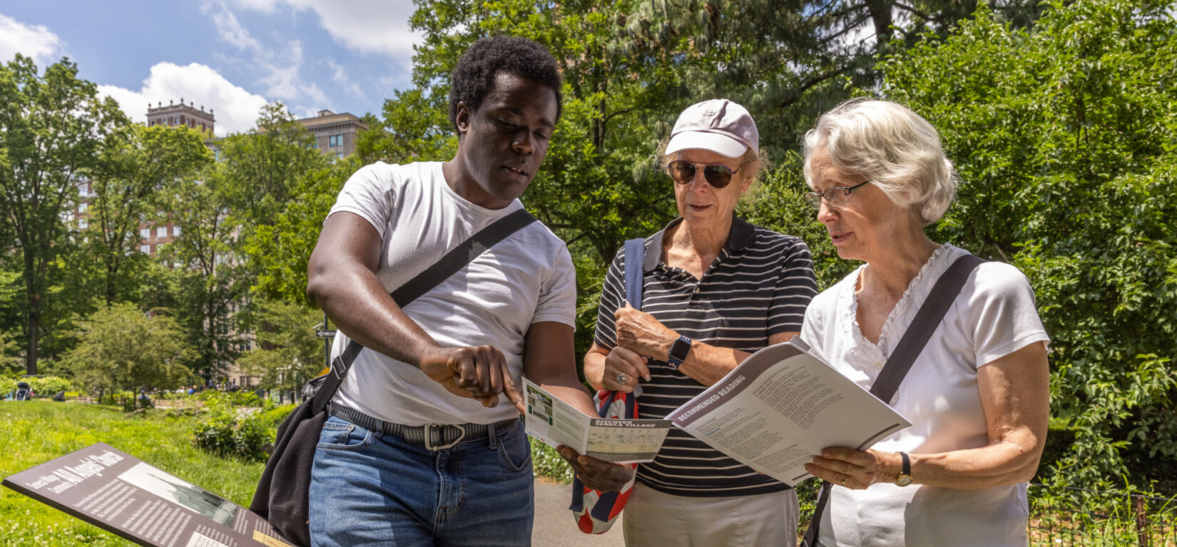 A group of people reading informational leaflets while touring Seneca Village