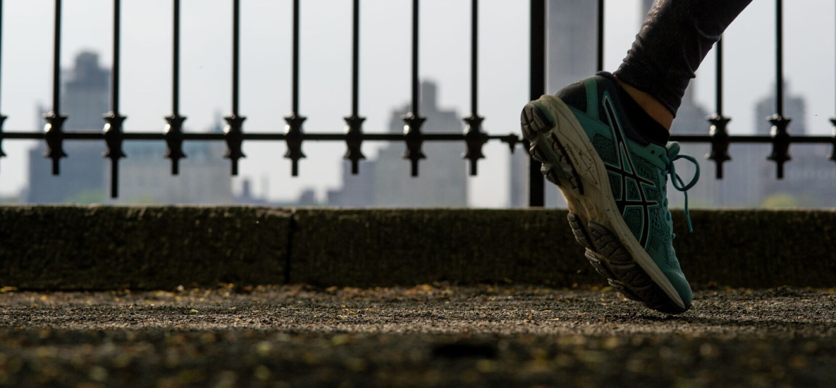 A close-up of a foot with the iron fence that surrounds the reservoir in the background