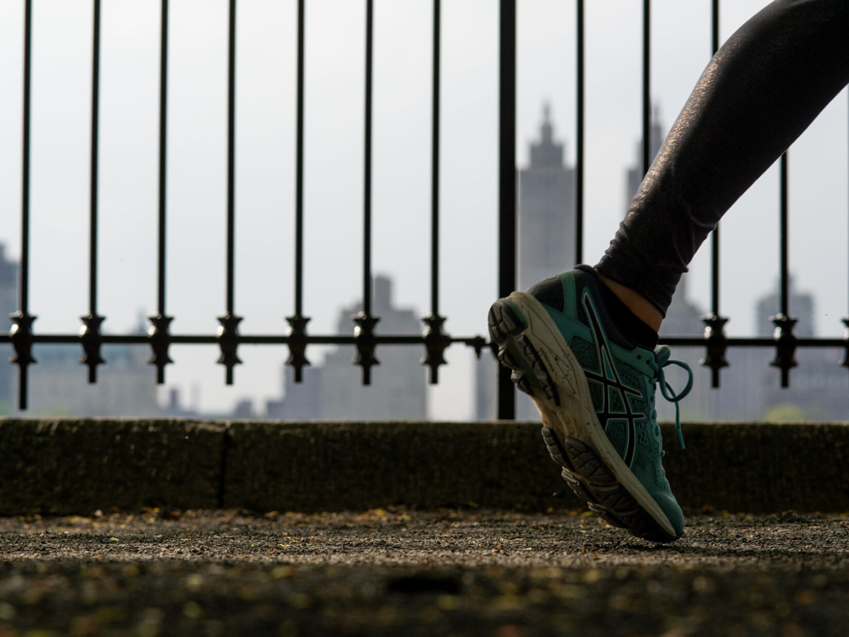 A close-up of a foot with the iron fence that surrounds the reservoir in the background