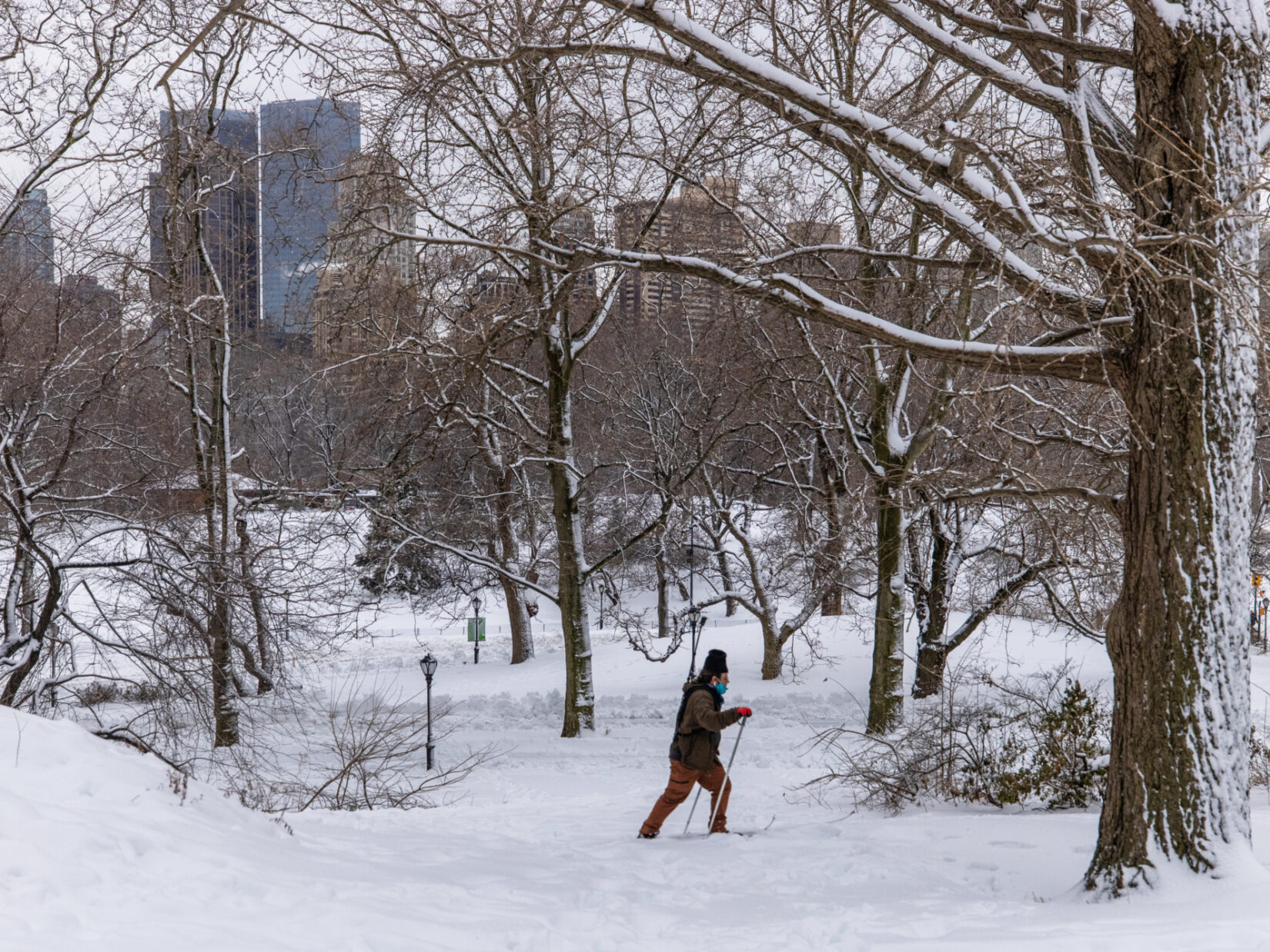 A person cross-country skis through a snowy landscape in Central Park.