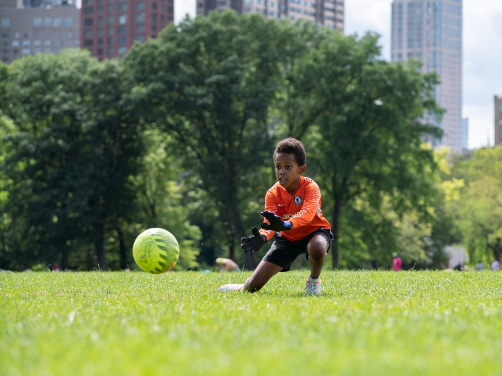 A young goalie keeps his eye on the ball on the North Meadow with the skyline in the background