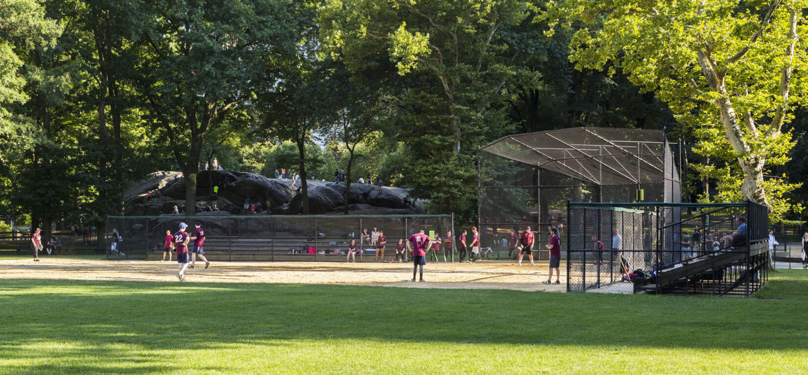 A summer softball game on Heckscher Ballfields with Umpire Rock looming in the background