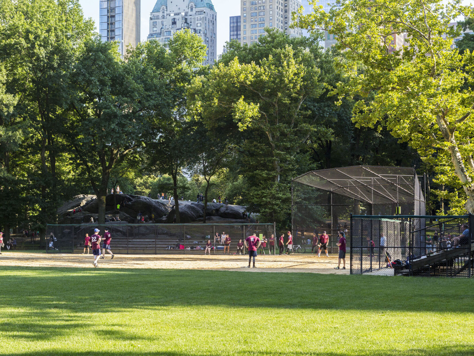 A summer softball game on Heckscher Ballfields with Umpire Rock looming in the background