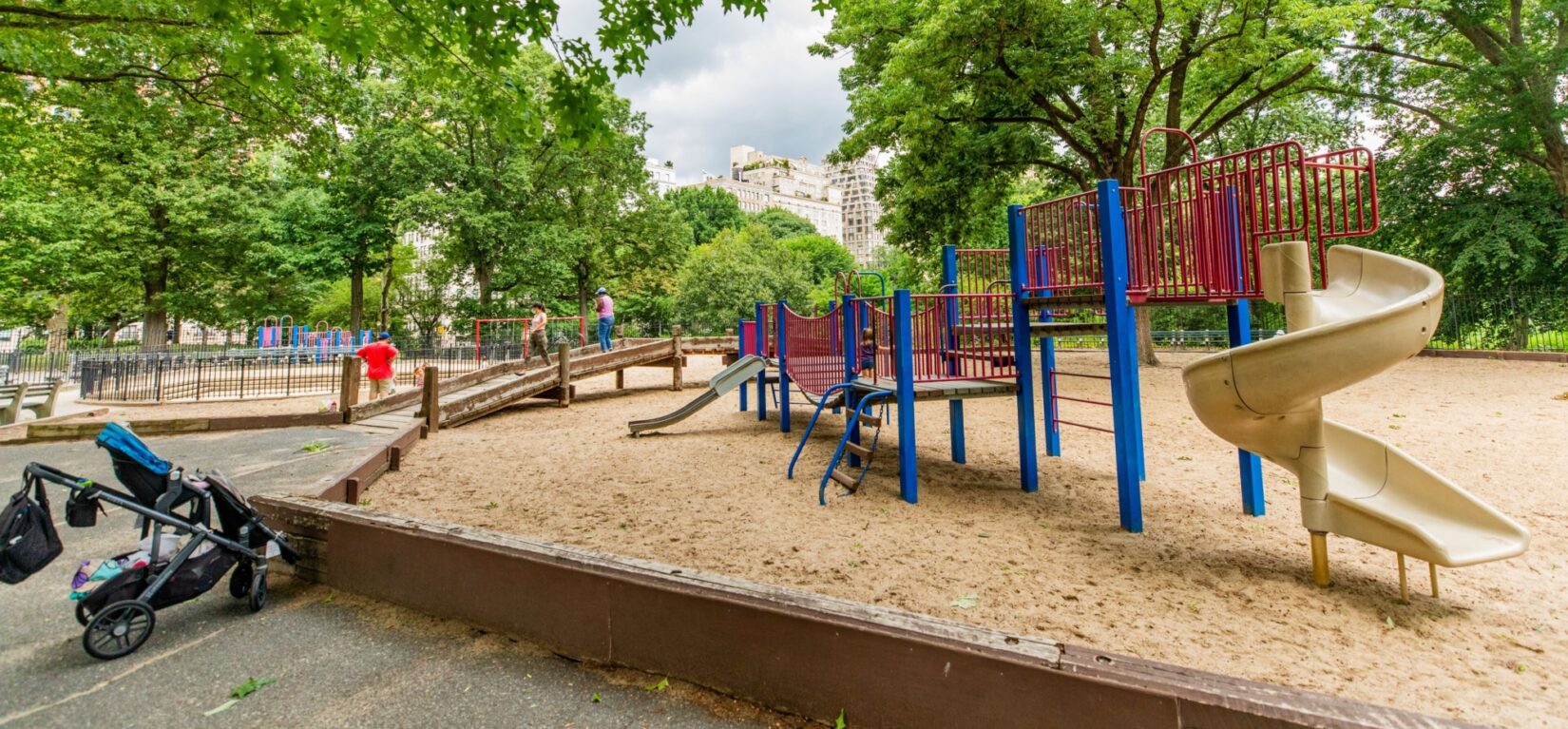 The climbing and sliding equipment in a large sandbox, seen in summer