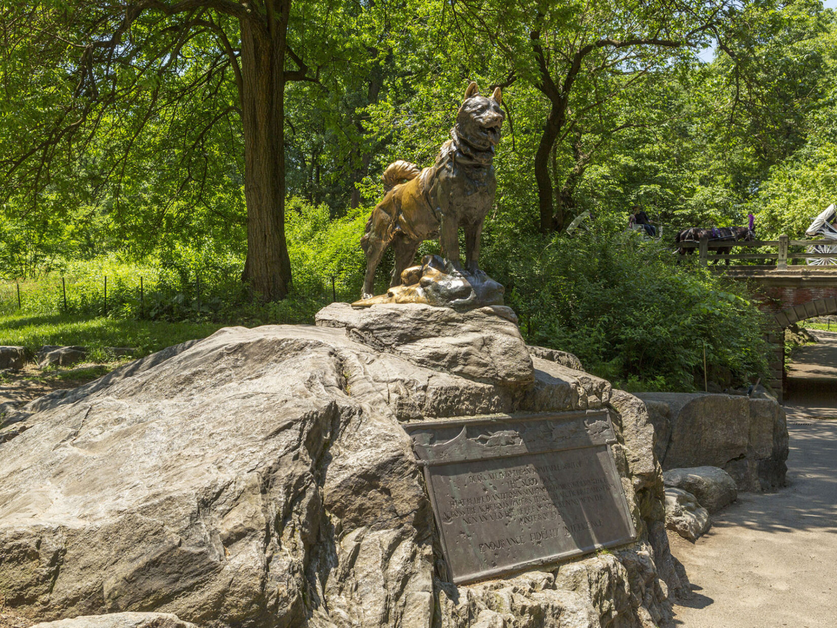 A photograph of the statue perched on an outcropping and the accompanying plaque