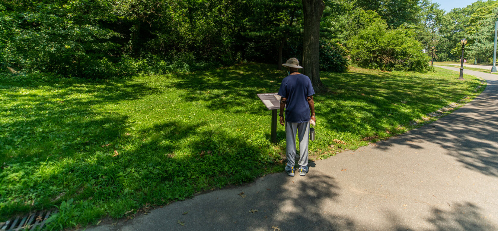 Park visitor reading Discover Seneca Village signage