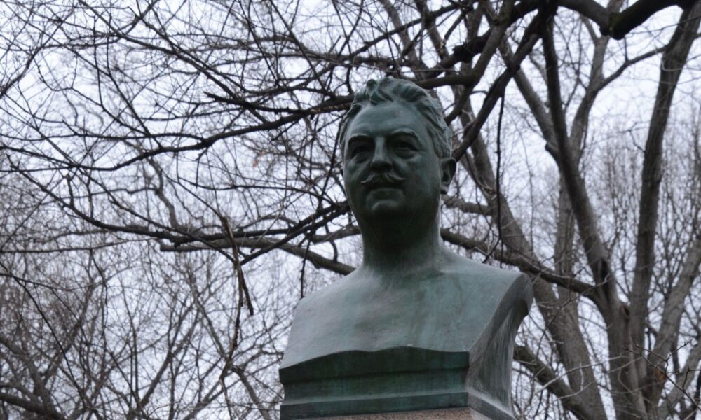 The bust is framed by a background of bare, winter branches