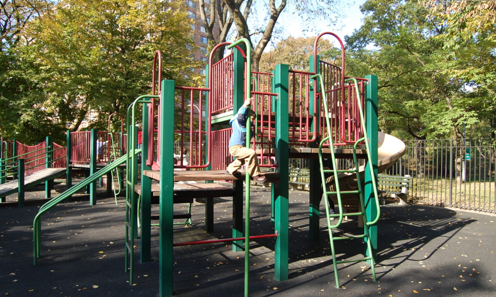 A child sliding down a pole on the side of a large cluster of climbing apparatus.